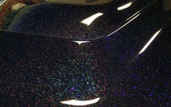 Black holographic metal flake on a car hood. Holographic flakes.